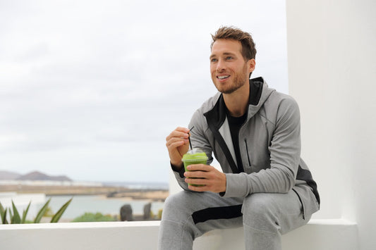 Young man in tracksuit drinking wheatgrass juice
